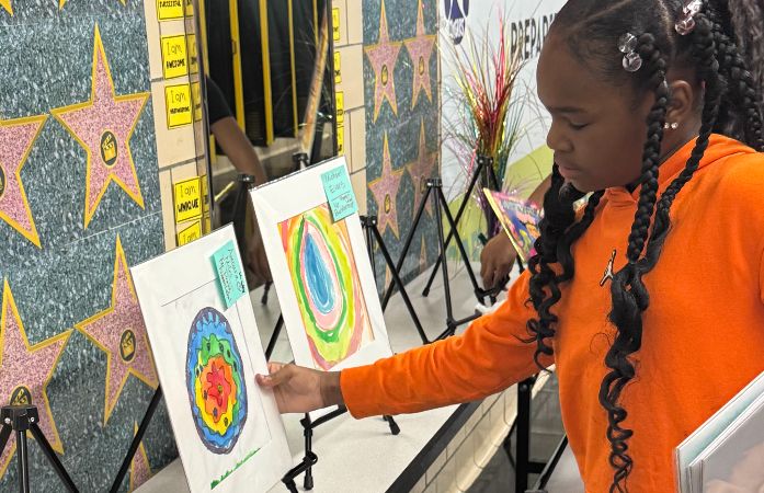 Student displaying artwork for the Mini Art Showcase at today's parent teacher conference.